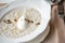 Bowl of breakfast oatmeal with soft Italian cheese and cinnamon. Croissants, coffee and other dishes on the table in the