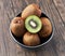 Bowl of bunch of kiwis and slice on a wooden table