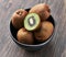 Bowl of bunch of kiwis and slice on a wooden table