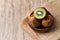 Bowl of bunch of kiwis and slice on a wooden table