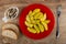 Bowl with canned herring, bread, slices of fried potato in red plate, fork on wooden table. Top view