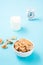 A bowl of cereal, a glass of milk and an alarm clock on a blue background. Scheduled breakfast. Vertical view