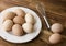 Bowl of chicken eggs, whisk, wooden background.