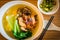 A bowl of chinese wanton noodle soup with chicken char siew and vegeatable on top
