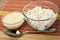 Bowl with condensed milk, transparent bowl with cottage cheese, spoon on bamboo mat