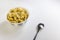 Bowl with corn flakes with spoon on white background