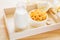 Bowl of cornflake and milk bottle on wooden tray