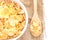 Bowl of cornflakes and cornflakes on wooden spoon over a sackcloth on white table background