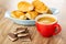 Bowl with croissants, pieces of chocolate with dairy porous filling, red cup with coffee on wooden table