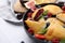 Bowl with delicious samosas, berries and mint leaves on white tiled table, closeup. Space for text