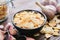 Bowl of dried garlic flakes. Heads of garlic and glass jar of garlic flakes on background.