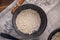 A bowl with dry flakes of oatmeal. Still life on textiles and wooden background.