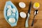 Bowl with egg shells, peeled egg, unpeeled chicken eggs, knife, salt shaker, spoon on wooden table. Top view