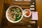 A bowl of famous Vietnamese pho noodle soup with rare beef, tendons, tripe and brisket, served with herbs. Intentional shallow