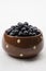 Bowl filled with bilberries, white background.