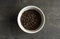 Bowl filled of fresh arabica or robusta coffee beans on a wooden table.