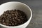 Bowl filled of fresh arabica or robusta coffee beans on a wooden table.