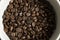 Bowl filled of fresh arabica or robusta coffee beans on a wooden table.