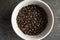 Bowl filled of fresh arabica or robusta coffee beans on a wooden table.