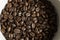 Bowl filled of fresh arabica or robusta coffee beans on a wooden table.