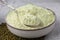 Bowl of flour, spoon and mung beans on light grey cloth, closeup