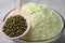 Bowl of flour, spoon and mung beans on light grey cloth, closeup