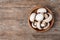 Bowl of fresh champignon mushrooms on wooden background, top view