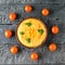 Bowl with fresh hummus and eight cherry tomatoes on a wooden table. The view from the top.