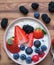 Bowl of fresh mixed berries and yogurt with farm fresh strawberries, blackberries and blueberries served on a wooden table