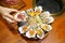 A bowl of Fresh Oyster topped with sea urchin roe uni, salmon roe ikura, wagyu beef, marinated egg yolk and spicy seafood
