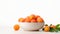 a bowl of fresh, ripe apricots with a branch and leaves vibrant orange hue against a white background