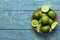 Bowl with fresh ripe limes on wooden background