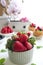 A bowl with fresh strawberries in the background kitchen decor, potted mint and fresh berries