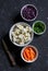 Bowl of fresh vegetables - red and cauliflower, carrots, green onions. On a dark stone background.