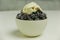 A bowl of frosty blackberries topped with honey yogurt in a white