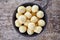 Bowl of frozen potato balls on wood, from above