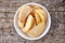 Bowl of frozen potato wedges on wood, from above