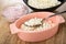 Bowl with fruit yogurt, black bowl with grained cottage cheese, spoon in oval bowl with cottage cheese on wooden table