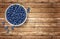 Bowl full of blueberries on wooden table.