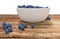 Bowl full of blueberries on wooden table.