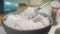 Bowl full of coarse sea salt. A spoon scoops up crystals in slow motion