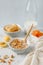 Bowl of granola with dried apricot on white table. Wooden spoon.