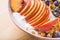 Bowl of granola with yogurt, peach slices and bluberry on a wooden table