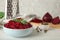 Bowl of grated boiled beets with basil and allspice on wooden table