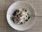 A bowl of Greek yoghurt with granola, blueberries, chia seeds and honey against a woven beige background