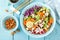 Bowl with grilled chicken meat, brown rice and fresh vegetable salad of avocado, radish, cabbage kale, carrot, and lettuce leaves