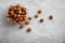 Bowl with hazelnuts on grey background, top view