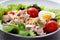 Bowl with healthy appetizing tuna salad with small tomatoes and lettuce leaves