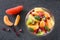 Bowl of healthy fresh fruit salad on black background