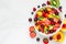 Bowl of healthy fresh fruit salad on white marble background. healthy food. top view